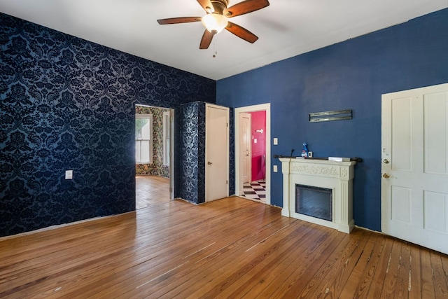 523 Ash St, Lockhart, TX 78644 - unfurnished living room with hardwood / wood-style floors, wallpapered walls, an accent wall, and a ceiling fan