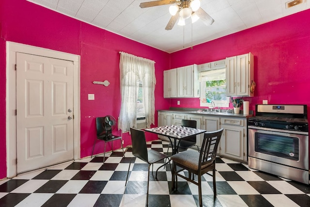 523 Ash St, Lockhart, TX 78644 - kitchen with gas stove, tile patterned floors, a ceiling fan, dark countertops, and a sink