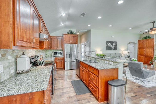 103 Ladera Cv, Marble Falls, TX 78654 - kitchen featuring stainless steel appliances, a sink, open floor plan, under cabinet range hood, and brown cabinets
