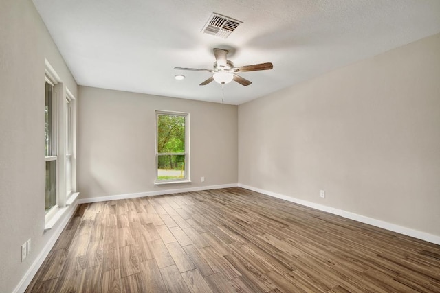 spare room with visible vents, baseboards, a ceiling fan, and wood finished floors