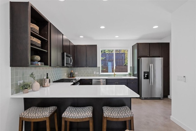 kitchen with open shelves, dark brown cabinetry, light countertops, stainless steel appliances, and backsplash