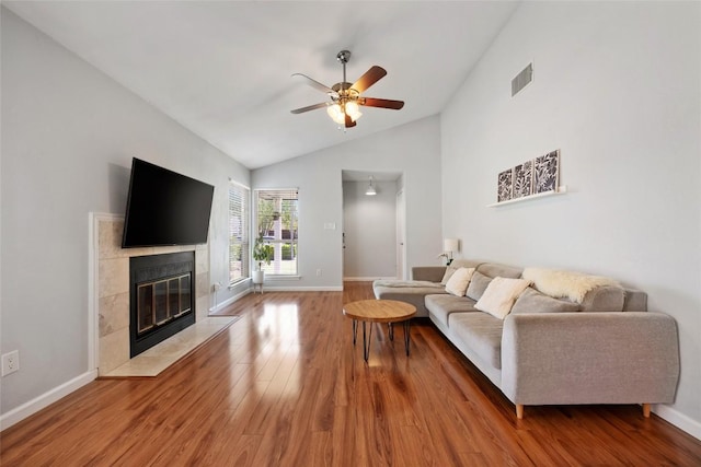 living room with lofted ceiling, wood finished floors, a ceiling fan, a high end fireplace, and baseboards