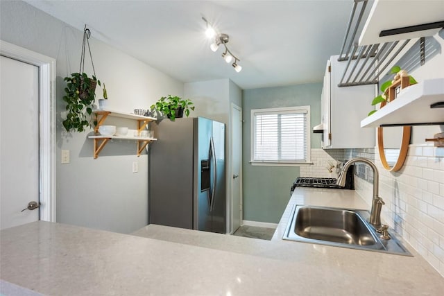 kitchen with open shelves, stainless steel fridge, a sink, and decorative backsplash
