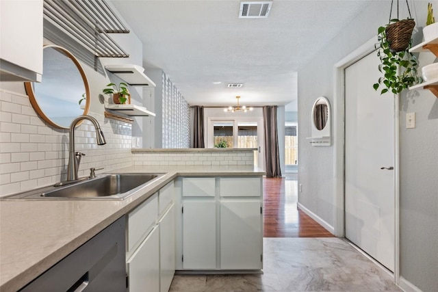 kitchen with open shelves, a sink, a peninsula, and decorative backsplash