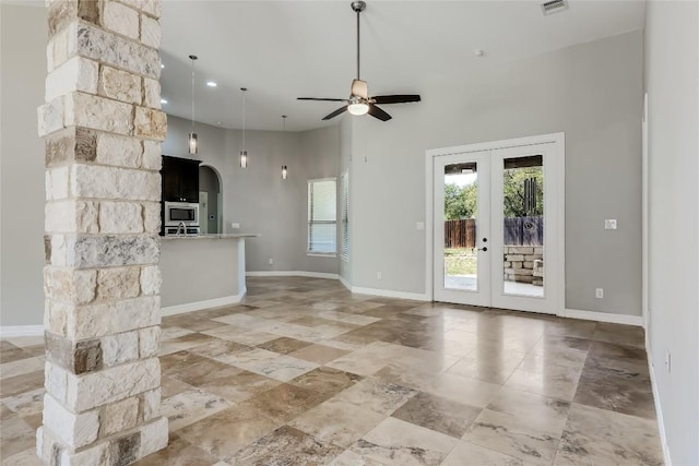 21434 Lakefront Dr, Lago Vista, TX 78645 - unfurnished living room with arched walkways, ceiling fan, french doors, a towering ceiling, and baseboards