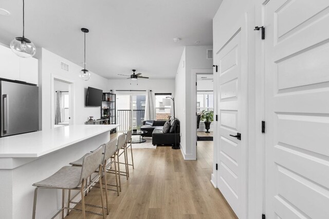 2500 Longview St Unit 418, Austin, TX 78705 - kitchen with stainless steel refrigerator, a kitchen bar, white cabinets, ceiling fan, and light wood-style flooring