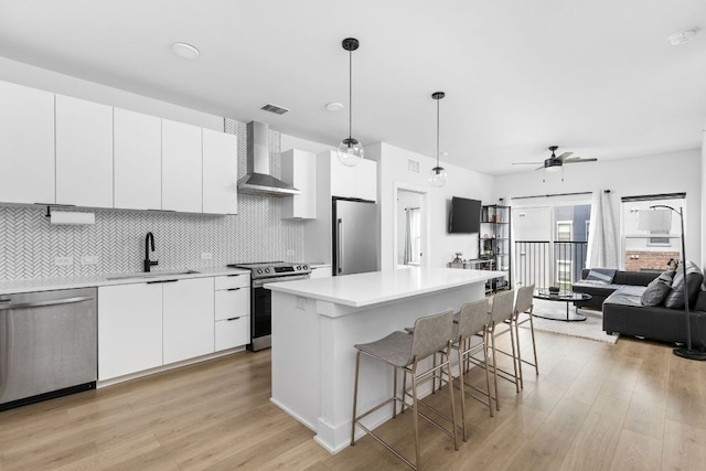 2500 Longview St Unit 418, Austin, TX 78705 - kitchen featuring wall chimney exhaust hood, stainless steel appliances, a sink, a breakfast bar area, and light wood-type flooring