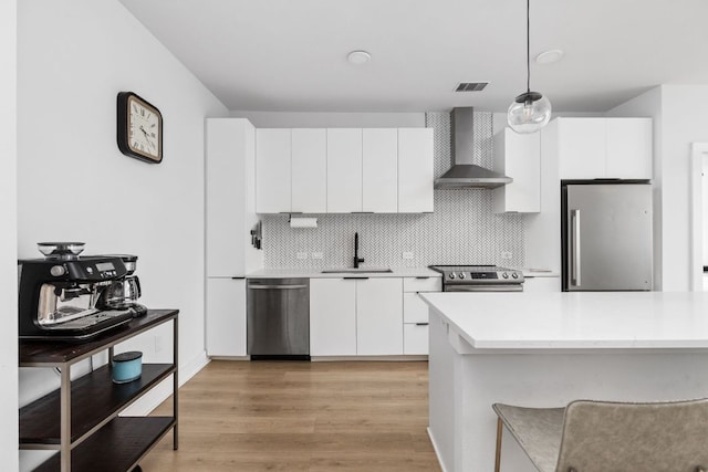 2500 Longview St Unit 418, Austin, TX 78705 - kitchen featuring stainless steel appliances, wall chimney range hood, a sink, light countertops, and white cabinetry