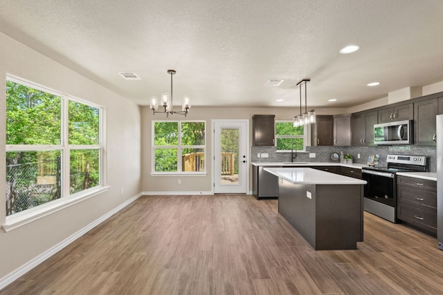 125 Channel Dr, Sunrise Beach, TX 78643 - kitchen featuring an inviting chandelier, light countertops, a kitchen island, baseboards, and appliances with stainless steel finishes