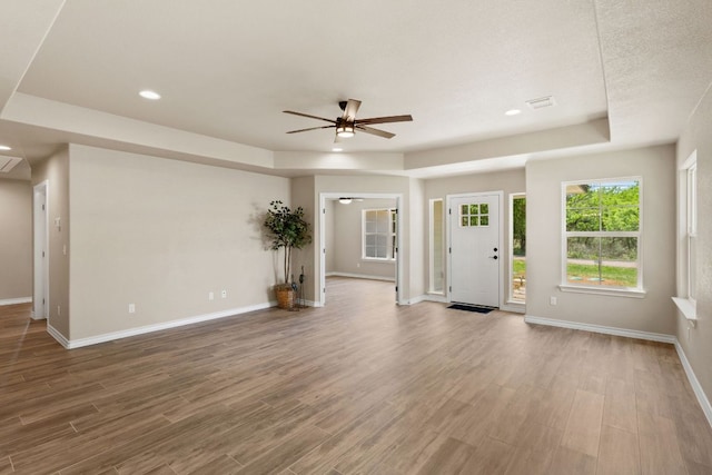 125 Channel Dr, Sunrise Beach, TX 78643 - unfurnished living room with recessed lighting, a tray ceiling, a ceiling fan, baseboards, and wood finished floors