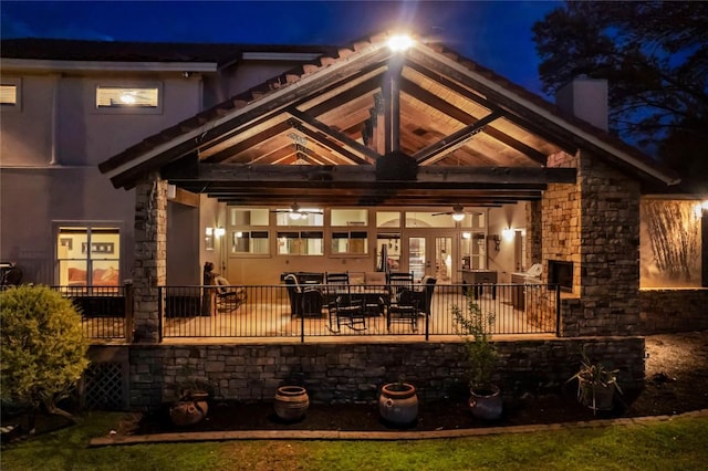 202 Bridgepoint Dr, Kingsland, TX 78639 - back of house at night featuring a patio area, a chimney, ceiling fan, and stone siding