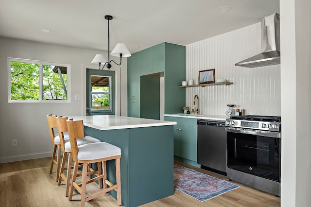 7614 Watson St, Austin, TX 78757 - kitchen with stainless steel appliances, wall chimney exhaust hood, light countertops, a sink, and light wood-type flooring
