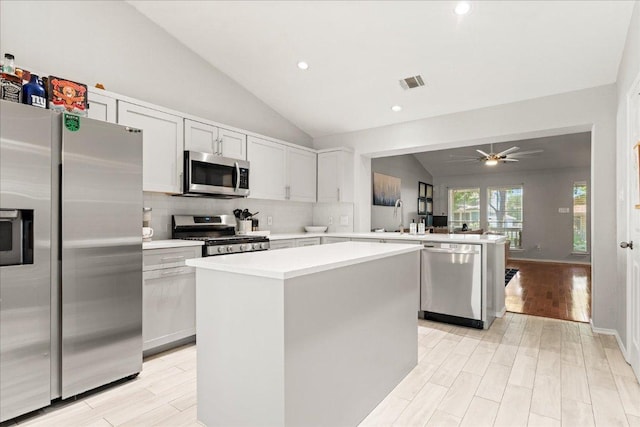 4456 Mather, Kyle, TX 78640 - kitchen with appliances with stainless steel finishes, a peninsula, lofted ceiling, a kitchen island, and light countertops