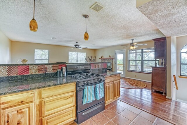 19818 Colina Dr, Lago Vista, TX 78645 - kitchen with black range with gas stovetop, ceiling fan, a textured ceiling, pendant lighting, and light tile patterned floors