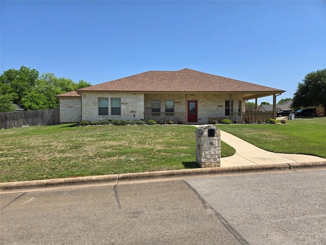 view of front of home featuring fence, a porch, a front yard, and stone siding