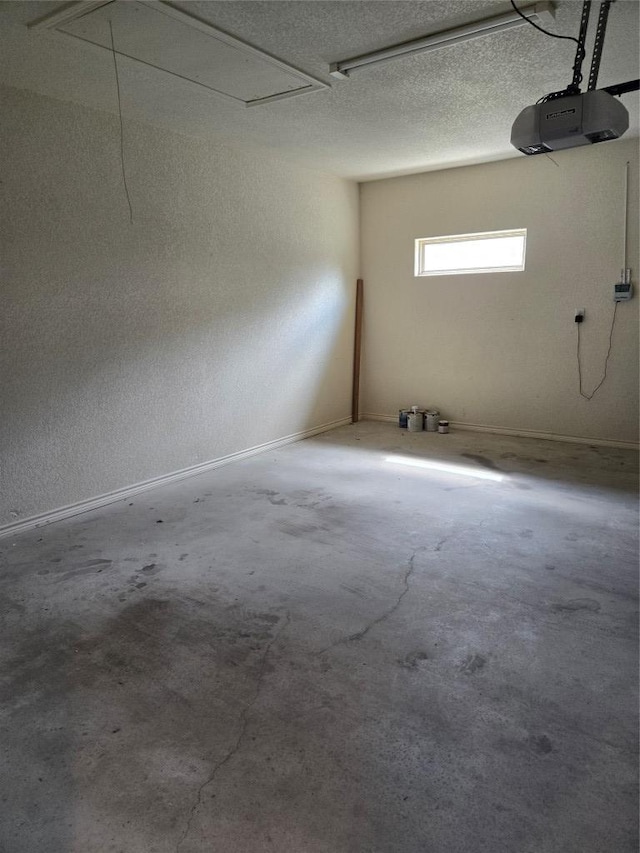 garage featuring a garage door opener, a textured wall, and baseboards