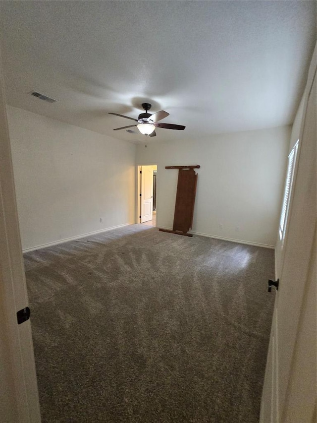 carpeted spare room with visible vents, a ceiling fan, and baseboards