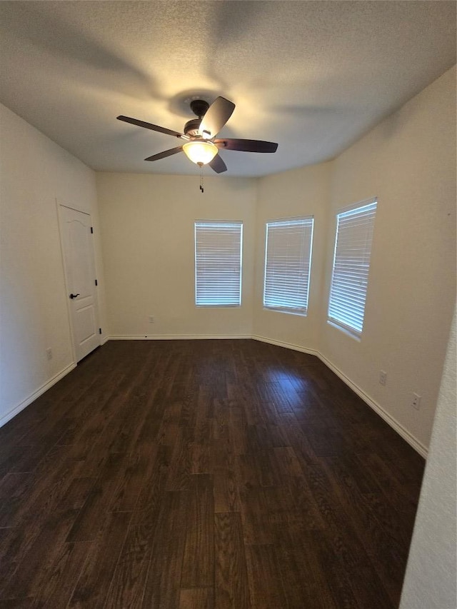 spare room featuring a ceiling fan, dark wood-style flooring, and baseboards
