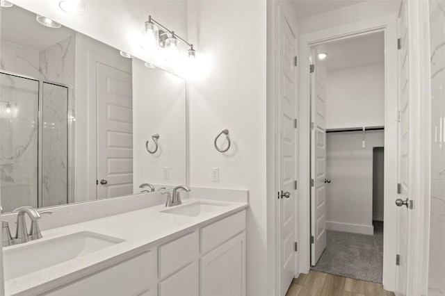 2031 Cora Ivy Ln, Round Rock, TX 78665 - bathroom featuring a marble finish shower, wood finished floors, double vanity, and a walk in closet