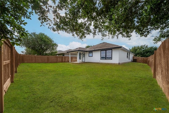 back of house with a fenced backyard and a lawn