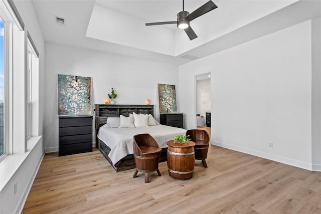 1890 Headwaters Blvd, Dripping Springs, TX 78620 - bedroom featuring a raised ceiling, multiple windows, light wood-style flooring, and ceiling fan