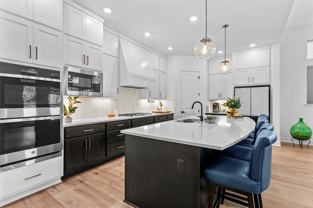 1890 Headwaters Blvd, Dripping Springs, TX 78620 - kitchen featuring appliances with stainless steel finishes, premium range hood, light wood-style floors, a kitchen bar, and decorative backsplash