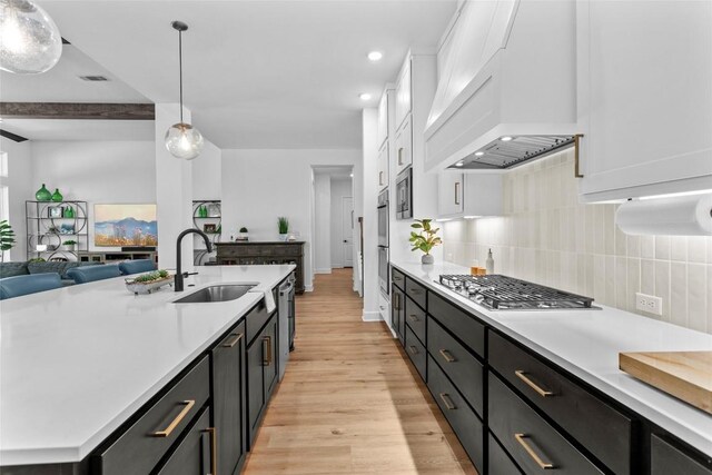 1890 Headwaters Blvd, Dripping Springs, TX 78620 - kitchen featuring appliances with stainless steel finishes, custom exhaust hood, light wood finished floors, white cabinetry, and light countertops