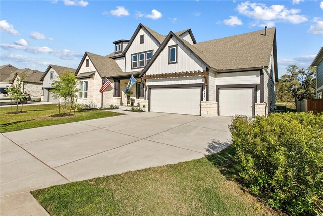 1890 Headwaters Blvd, Dripping Springs, TX 78620 - view of front of house with concrete driveway, board and batten siding, a front lawn, stone siding, and a garage