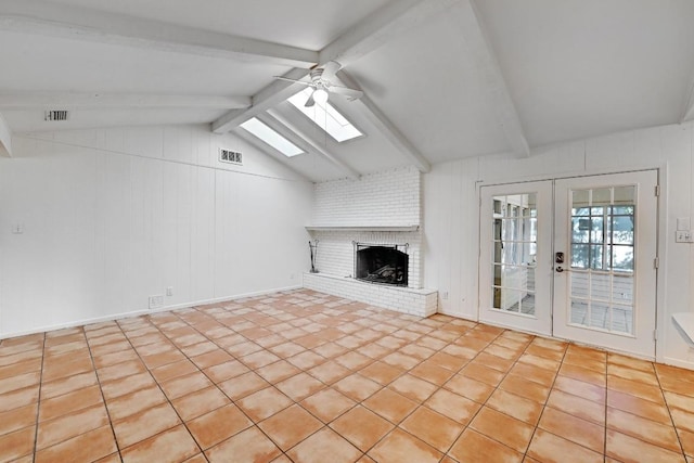 1700 Barton Hills Dr, Austin, TX 78704 - unfurnished living room with ceiling fan, french doors, a skylight, a brick fireplace, and tile patterned flooring