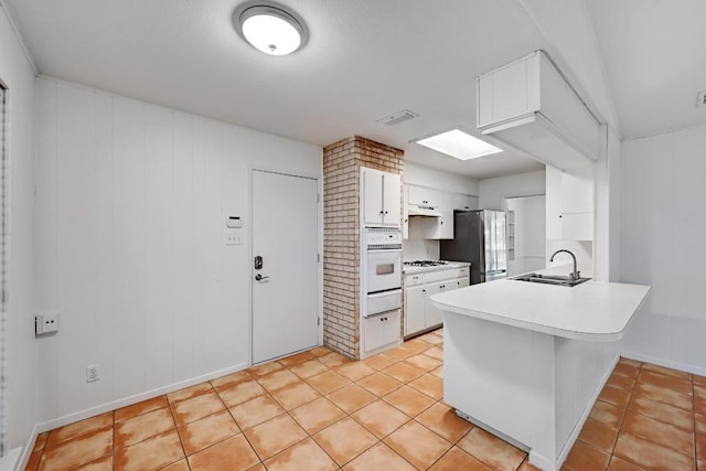 1700 Barton Hills Dr, Austin, TX 78704 - kitchen featuring a warming drawer, freestanding refrigerator, oven, a peninsula, and white cabinetry