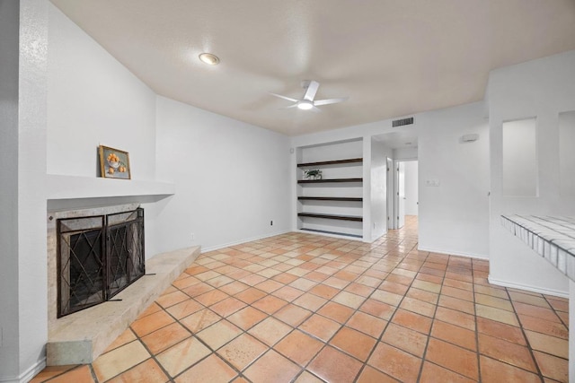 8200 Neely Dr Unit 103, Austin, TX 78759 - unfurnished living room featuring a ceiling fan, a fireplace with raised hearth, built in shelves, tile patterned flooring, and baseboards