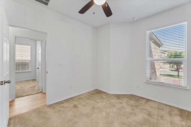 spare room with visible vents, ceiling fan, light colored carpet, and baseboards