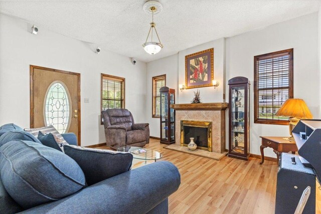 406 Garwood St, Smithville, TX 78957 - living area featuring light wood finished floors, a tile fireplace, baseboards, and a textured ceiling