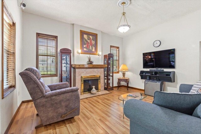 406 Garwood St, Smithville, TX 78957 - living area with light wood-style floors, baseboards, a textured ceiling, and a tiled fireplace