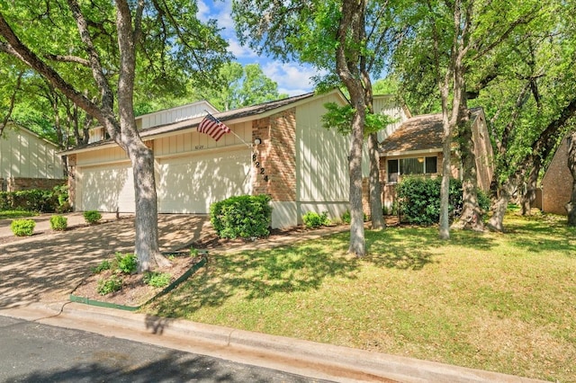 view of front of home with brick siding, a garage, driveway, and a front yard