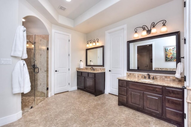 full bathroom with a stall shower, two vanities, a sink, and visible vents