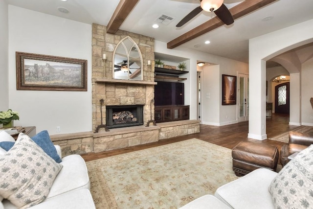 living area featuring visible vents, beamed ceiling, ceiling fan, arched walkways, and wood finished floors