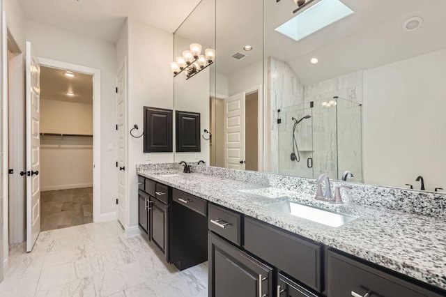 full bathroom with a shower stall, a spacious closet, a sink, and a skylight