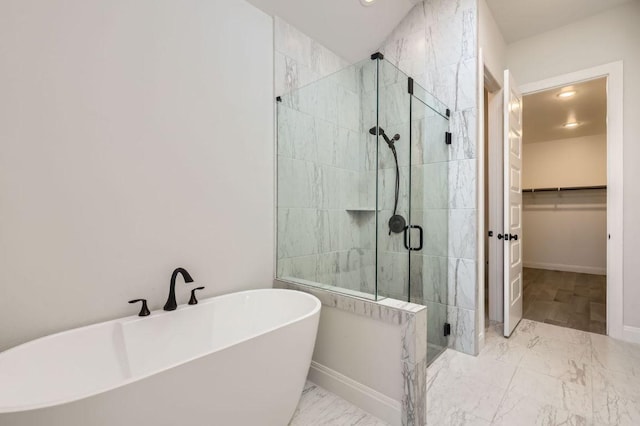 full bath featuring a soaking tub, marble finish floor, a walk in closet, a stall shower, and baseboards