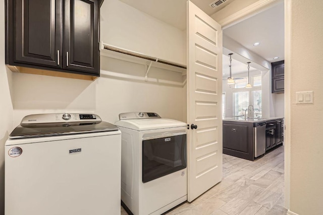 washroom with washing machine and clothes dryer, a sink, cabinet space, and recessed lighting