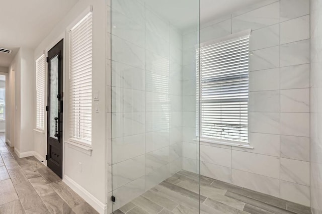 bathroom with visible vents, baseboards, and walk in shower