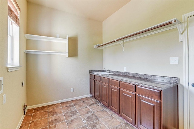laundry area with cabinet space, baseboards, electric dryer hookup, and a sink