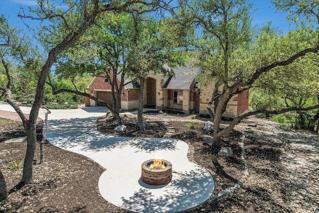 view of yard featuring a fire pit, a garage, and concrete driveway