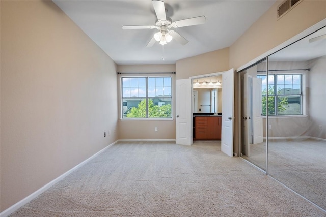 unfurnished bedroom featuring baseboards, multiple windows, and light colored carpet
