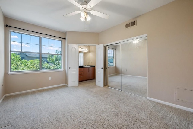 unfurnished bedroom featuring light colored carpet, baseboards, multiple windows, and visible vents