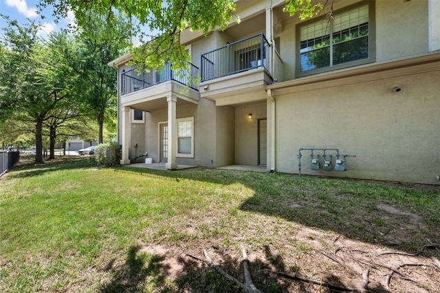 back of property with a yard, a balcony, and stucco siding