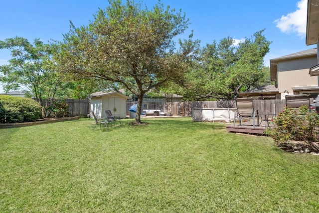 view of yard with an outbuilding, a fenced backyard, a wooden deck, and a shed