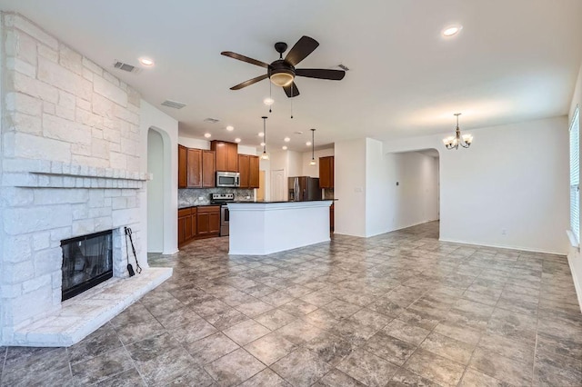 unfurnished living room featuring visible vents, a stone fireplace, baseboards, and ceiling fan with notable chandelier