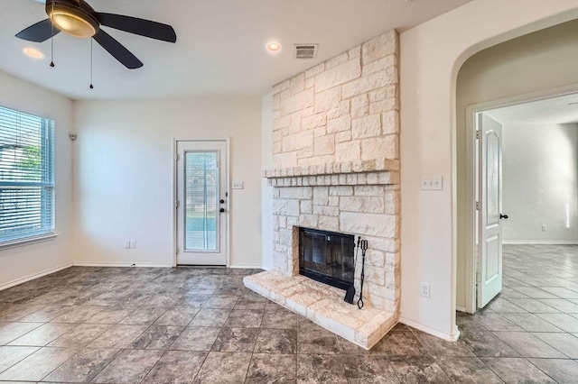 1161 Verna Brooks Way, Kyle, TX 78640 - unfurnished living room with a stone fireplace, ceiling fan, arched walkways, and baseboards