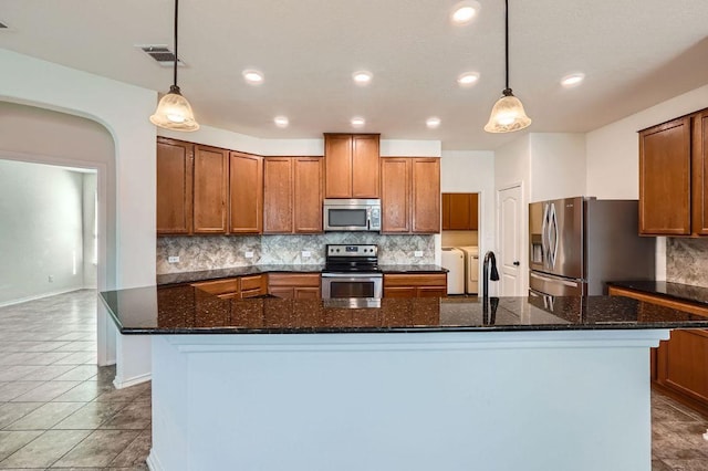 kitchen with visible vents, washing machine and clothes dryer, stainless steel appliances, brown cabinets, and decorative backsplash